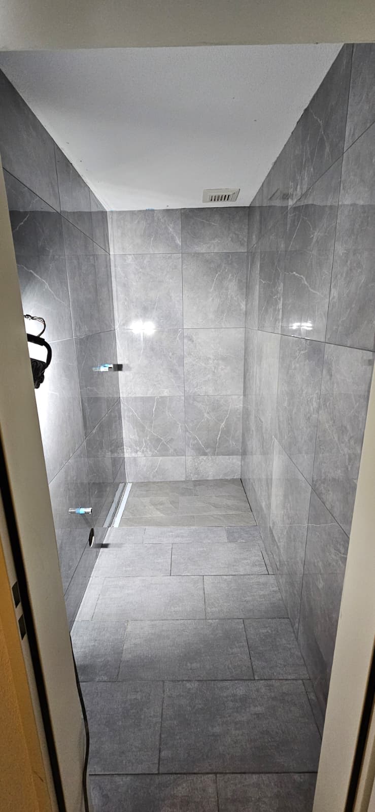 Bodenebene Dusche mit Linienentwässerung in heller Marmoroptik