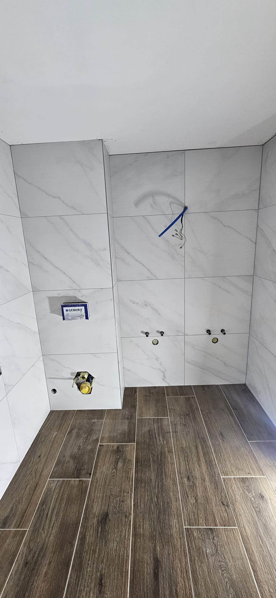 Bad mit Marmoroptik-Wandplatten und Holzoptik-Boden, Geberit-Vorwand