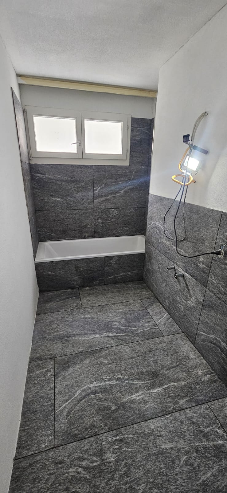 Badezimmer mit Wanne und grauen 120×60 Platten in Natursteinoptik